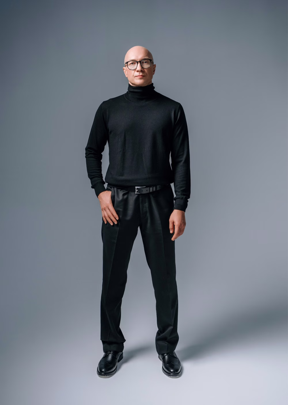 The surgeon standing, in a black turtleneck